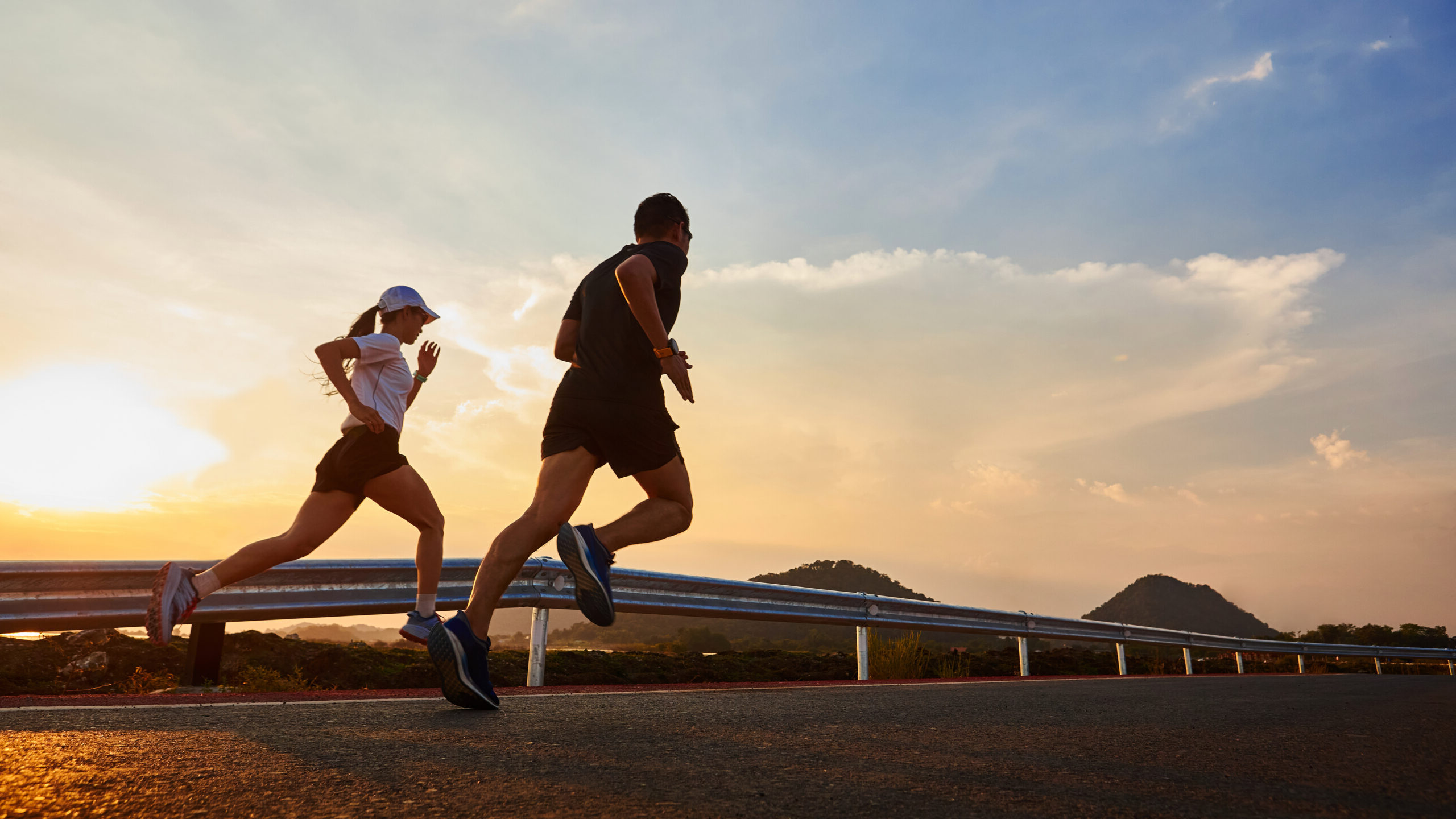 Two people jogging on the street at sunset. Two men and women jogging in casual wear jogging on the road at sunset.
